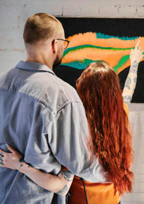 a man and a woman looking at a painting on a wall