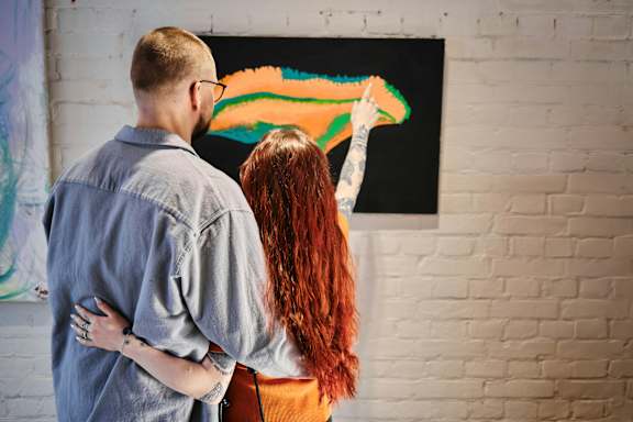 A man and a woman are painting a picture on a black canvas.