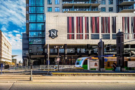 a city street with a train in front of a tall building