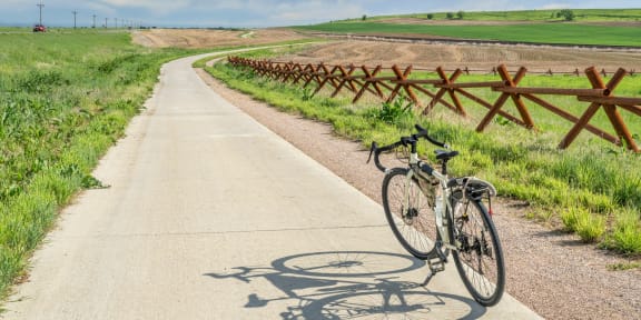 a bike parked on the side of a trail next to a field