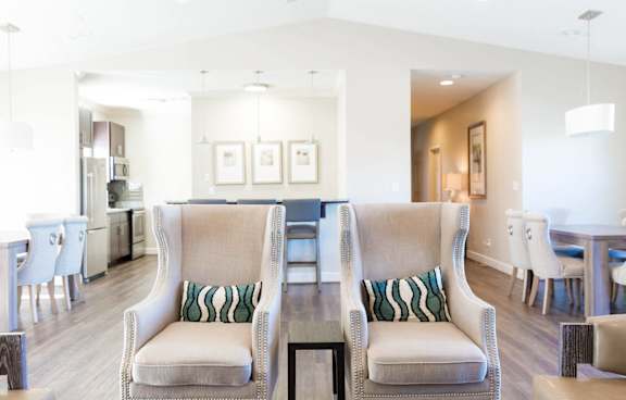 Two white chairs with cushions are in the middle of a room.