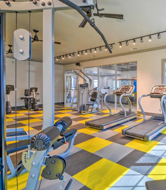 a gym with cardio machines and weights on a checkered floor at The Atlantic Station, Ft Worth, Texas