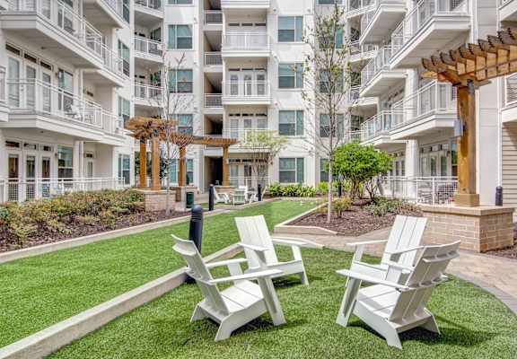 a courtyard with chairs and tables in front of an apartment building