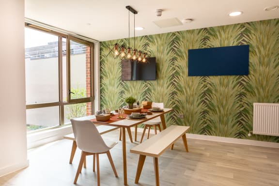 a dining room with a table and chairs and a wall mural of palm trees