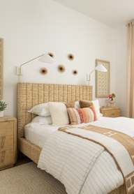 A bedroom with a bed, nightstand, and a plant.