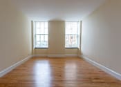 Thumbnail 2 of 23 - A room with wooden floors and two windows.