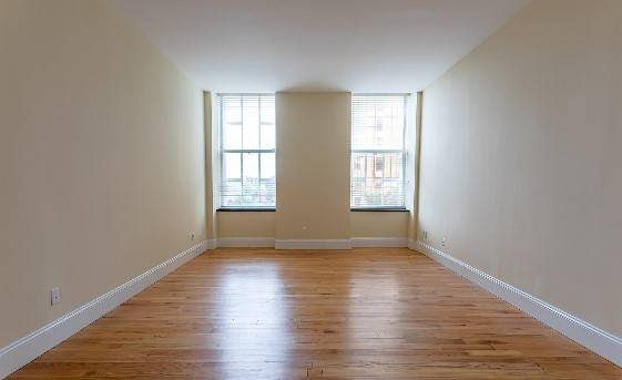 A room with wooden floors and two windows.