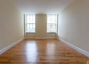 Thumbnail 2 of 23 - A room with wooden floors and two windows.
