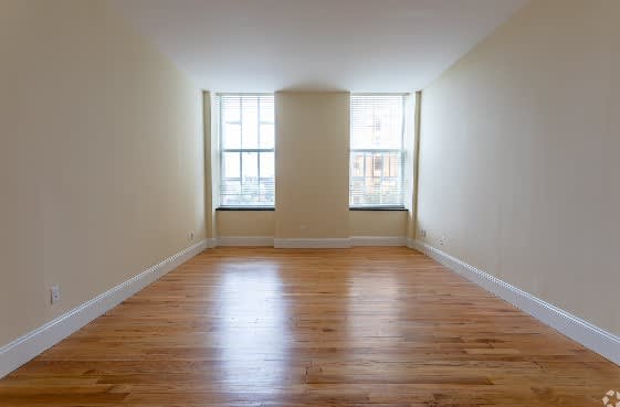 A room with wooden floors and two windows.