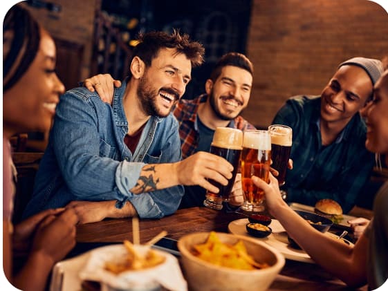 a group of friends sitting around a table drinking beer