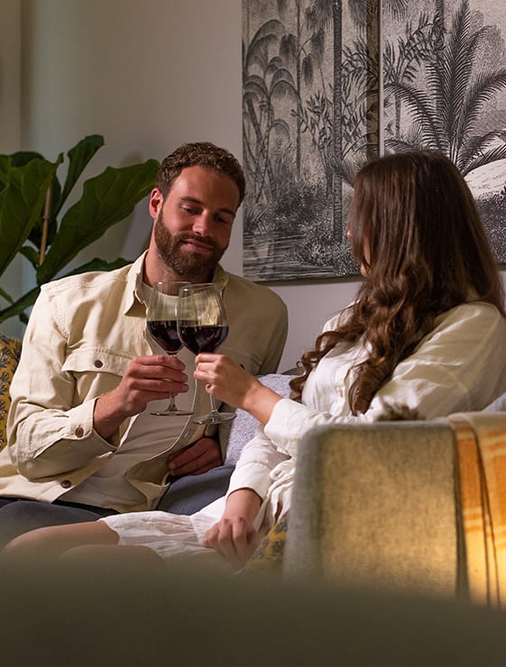 a man and a woman sitting on a couch with a glass of wine