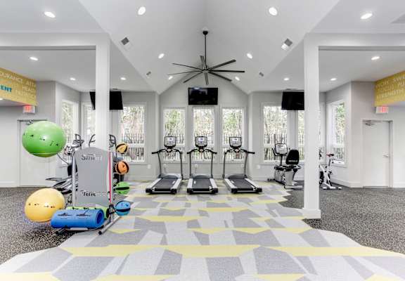 A gym with a variety of equipment including treadmills, exercise balls, and weights.