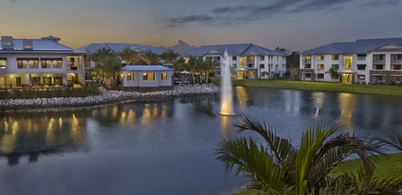 a large pond with a fountain in front of some houses
