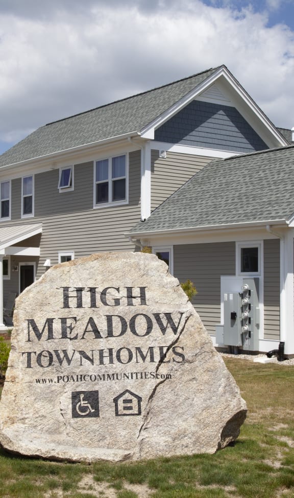 a large rock in front of a house with a sign for high meadow apartments
