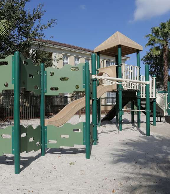A playground with a green slide and a brown slide.