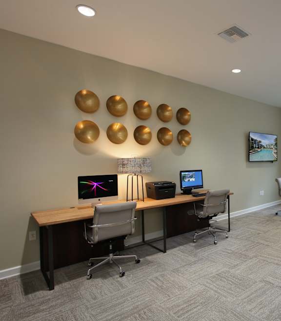 A conference room with a long table and chairs, a computer desk, and a wall with circular lights.