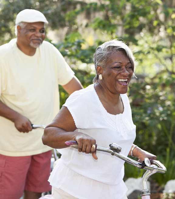 an older woman riding a bike with a man walking behind her