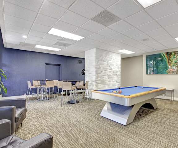 A resident lounge with tables, chairs, and a pool table at Capitol Towers - Towers and Villas