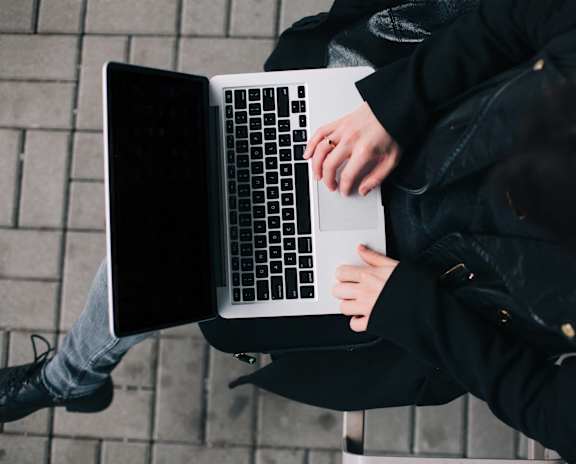 A person in a black jacket is using a laptop.