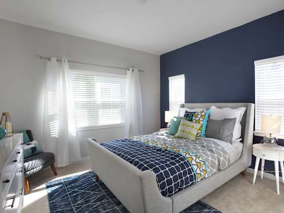 A bedroom with a bed, a chair, and a window with curtains.