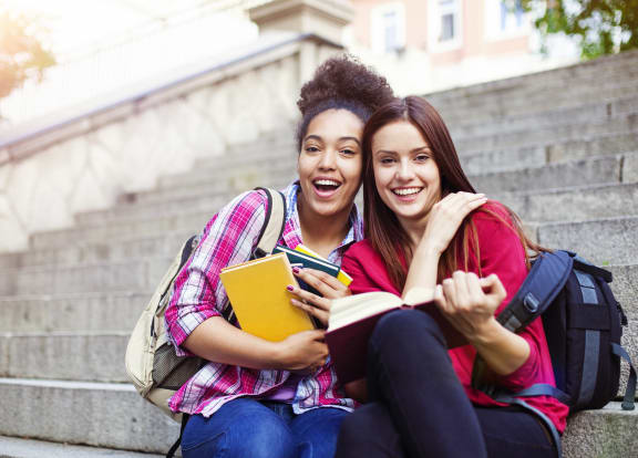 two girls sitting on the steps reading a book at Midtown Sam Houston Apartments, Huntsville, TX, 77340