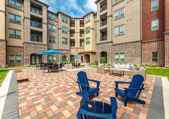 A patio with blue chairs and a table with a blue umbrella.