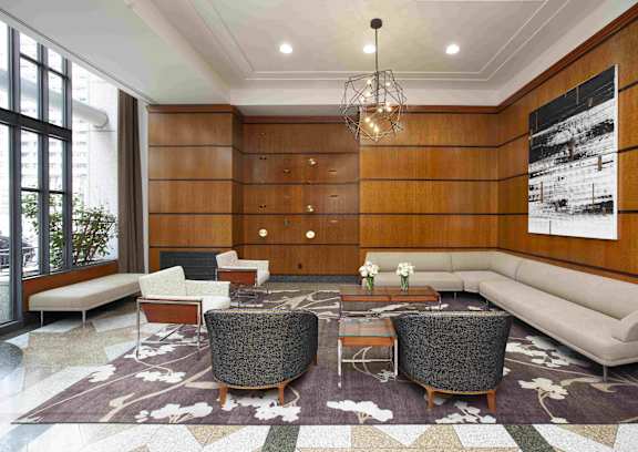 A living room with a grey sofa, a grey armchair, a white coffee table and a rug with a floral pattern.