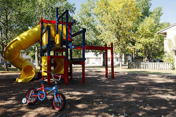 a playground with a yellow slide and a bike