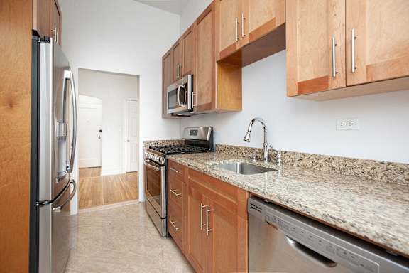 A kitchen with a granite counter top and stainless steel appliances.at Sutton Collection, New York, 10022