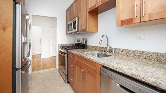 A kitchen with a granite counter top and stainless steel appliances.at Sutton Collection, New York, 10022