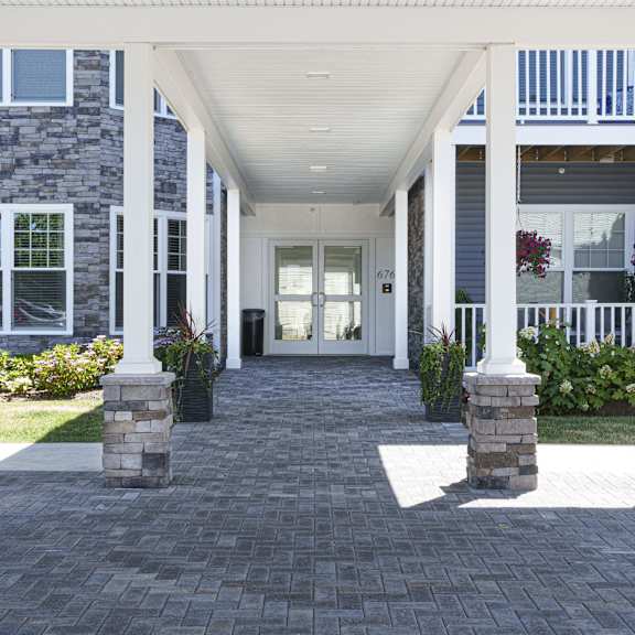 the front porch of a home with a brick walkway and columns