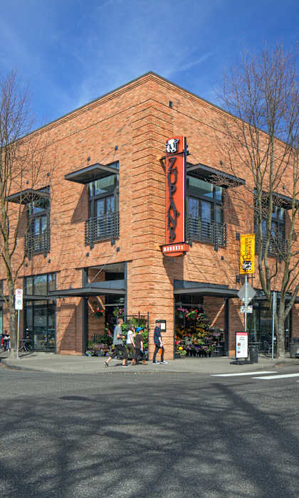 A red brick building with a yellow awning sits at a street corner.