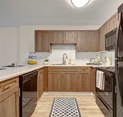 an empty kitchen with wooden cabinets and a black refrigerator