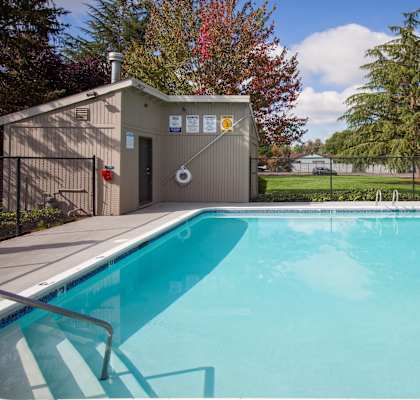 A small pool with a diving board and a small building next to it.