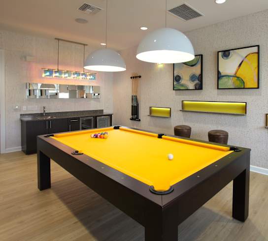 A pool table with a yellow cloth and a white cue ball in the middle.