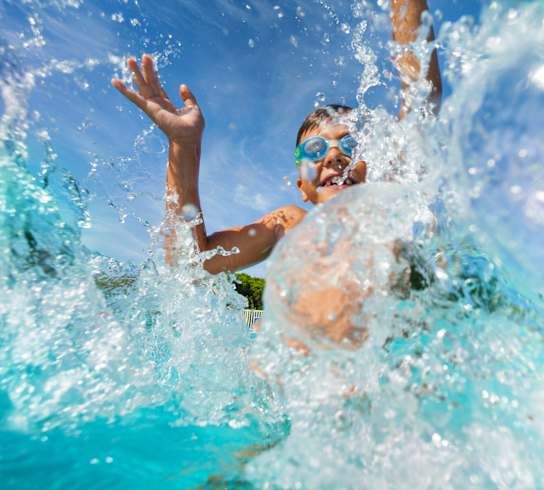 A person swimming in a pool with water splashing around.