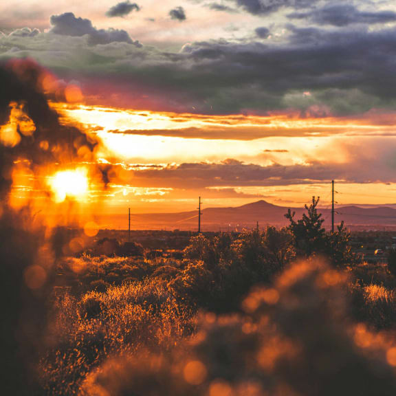 the sun sets over the desert with mountains in the background