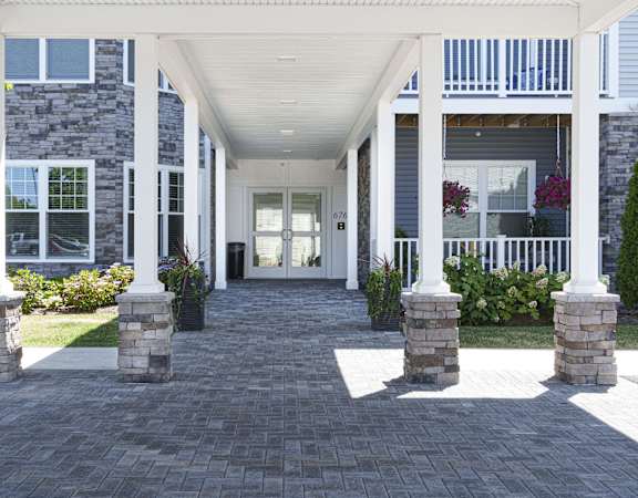 the front porch of a home with a brick walkway and columns