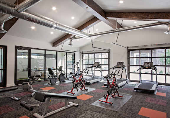 A gym with a variety of equipment including treadmills, stationary bikes, and weight benches.