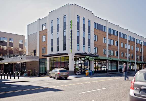 A street view of a building with cars driving by.