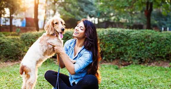 a woman sitting on the grass with her dog