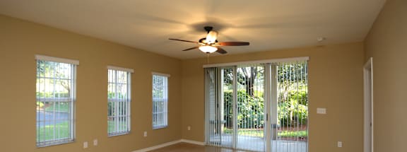 A spacious room with a ceiling fan and sliding glass doors.