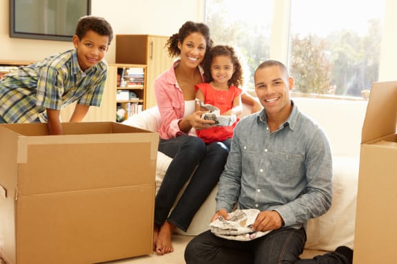 a family sitting on a couch with cardboard boxes