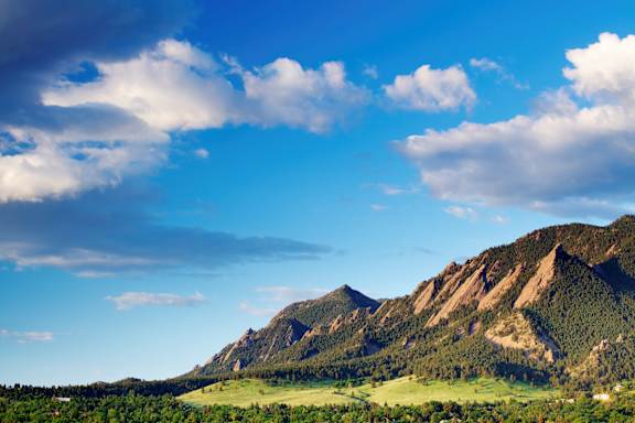 A mountain range with greenery and clouds in the sky.