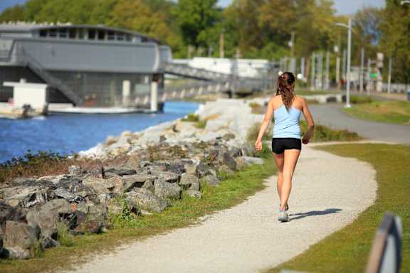 A woman is jogging on a path near a body of water.