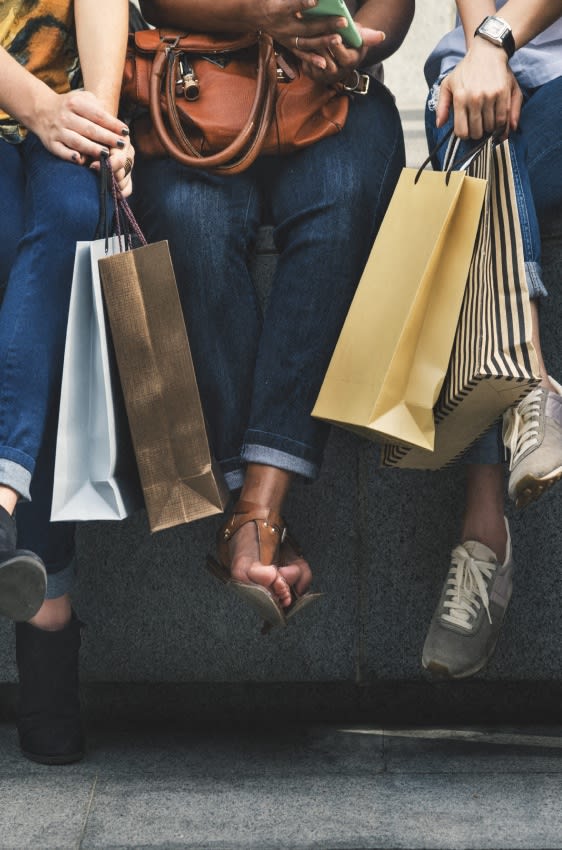 three people sitting on a bench holding shopping bags at West Woods, Annapolis, Maryland