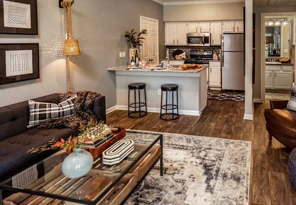 A modern kitchen with a black couch and a glass coffee table.