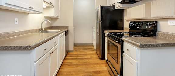 A kitchen with white cabinets and a black refrigerator.