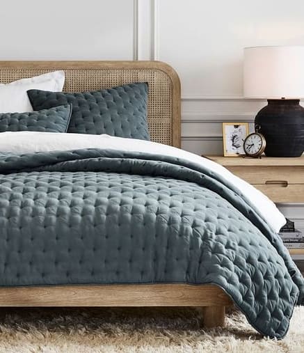 a bedroom with a bed with a grey comforter and pillows