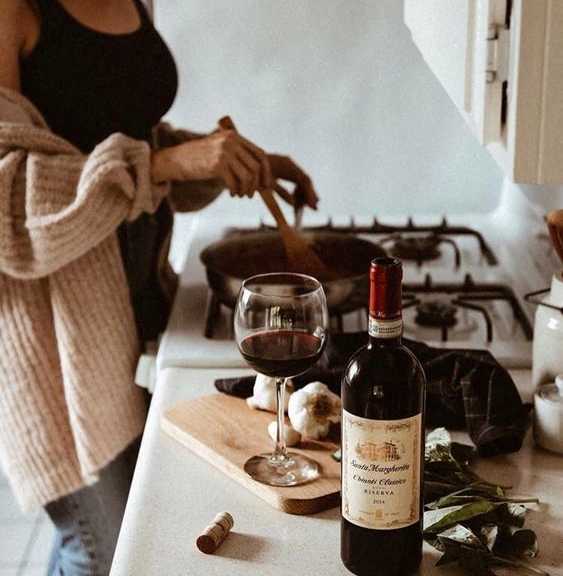 a woman cooking in a kitchen with a glass of wine at Copestone Apartments, Garden City, 59808